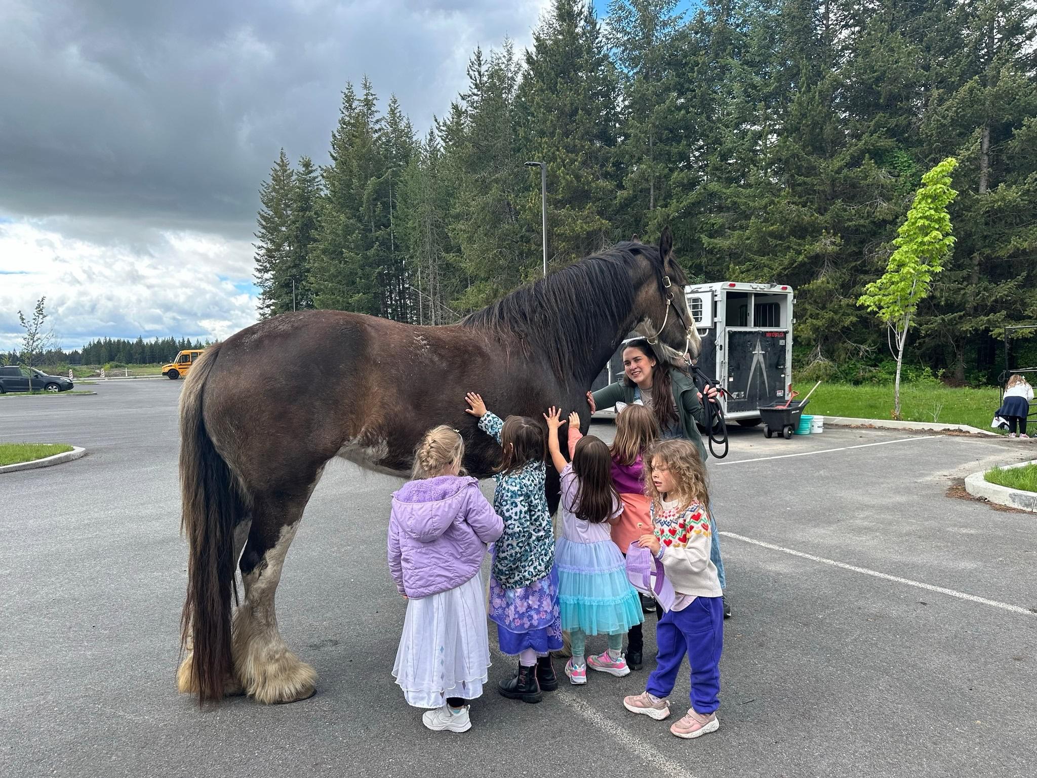 Children petting a Clydesdale horse with a Tribal Cowboy handler at a North Idaho school program